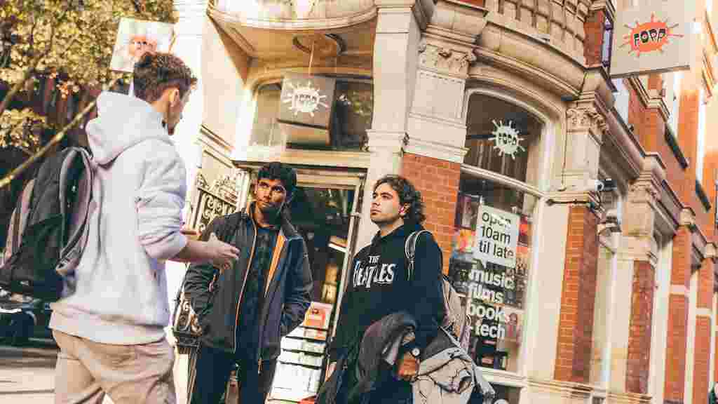 Three male students chatting outside shop