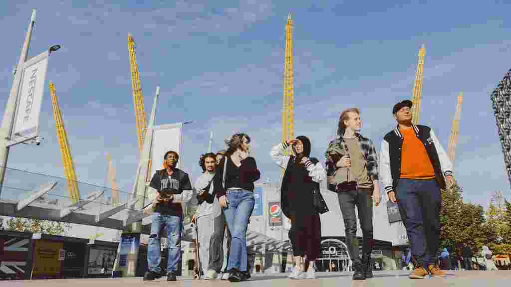 Group of students walking through North Greenwich with O2 arena in background