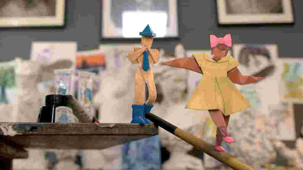 Two paper characters walking along a paintbrush tightrope