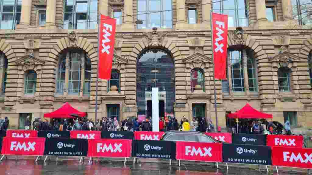 Exterior of FMX conference building with branded flags and signs