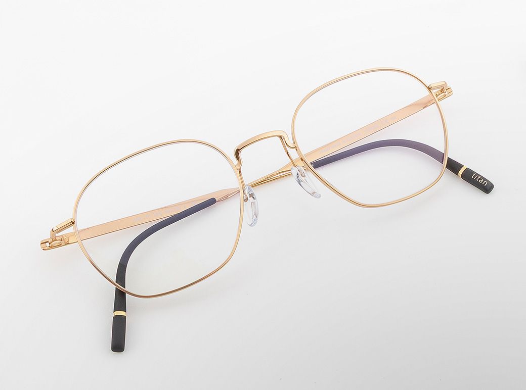 Pure Visionary titanium eyeglasses with an ultra-thin gold profile wire frame, softly geometric lenses, a sculpted bridge, and lightweight temples with black temple tips.