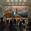 People taking pictures in an art gallery but the image is Laufey from God of War