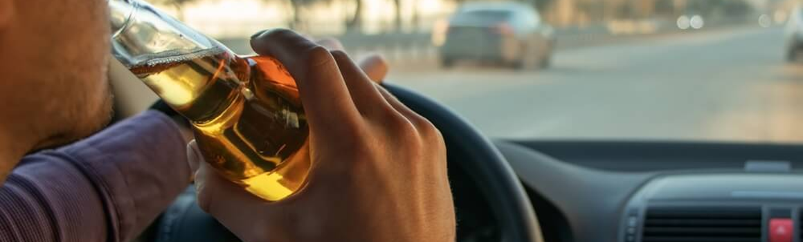 Muž pije pivo při řízení auta