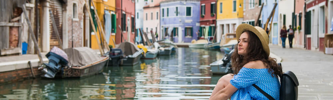 Žena sedí u kanálu v Benátkách v Itálii