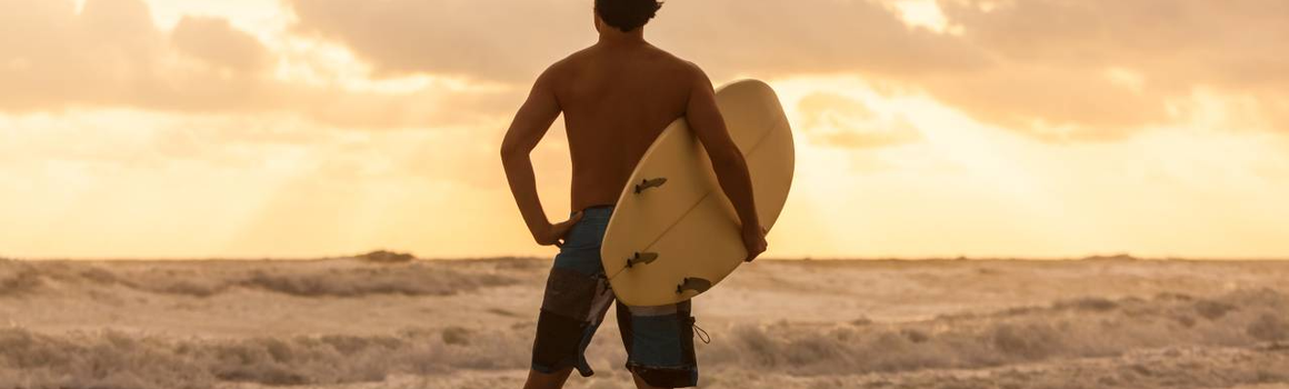 Surfař se dívá na západ slunce