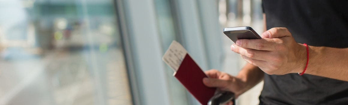 Muž s letenkami, pasem a mobilním telefonem na letišti