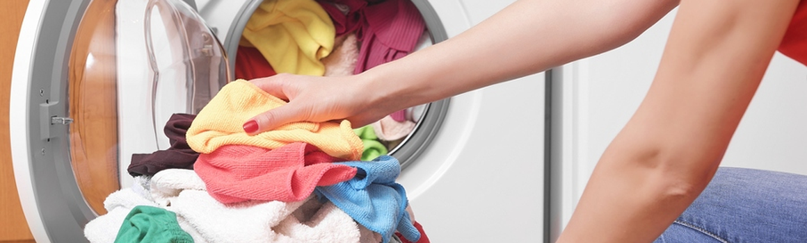 Žena plní pračku špinavým prádlem