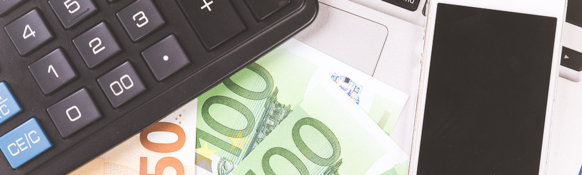 peniaze, kalkulačka, mobil a notebook na stole