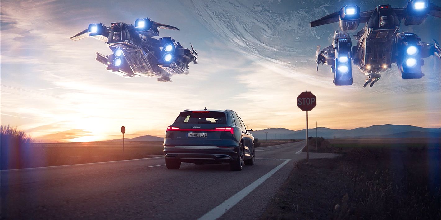 Audi waiting at a stop sign with two space ships flxing over it