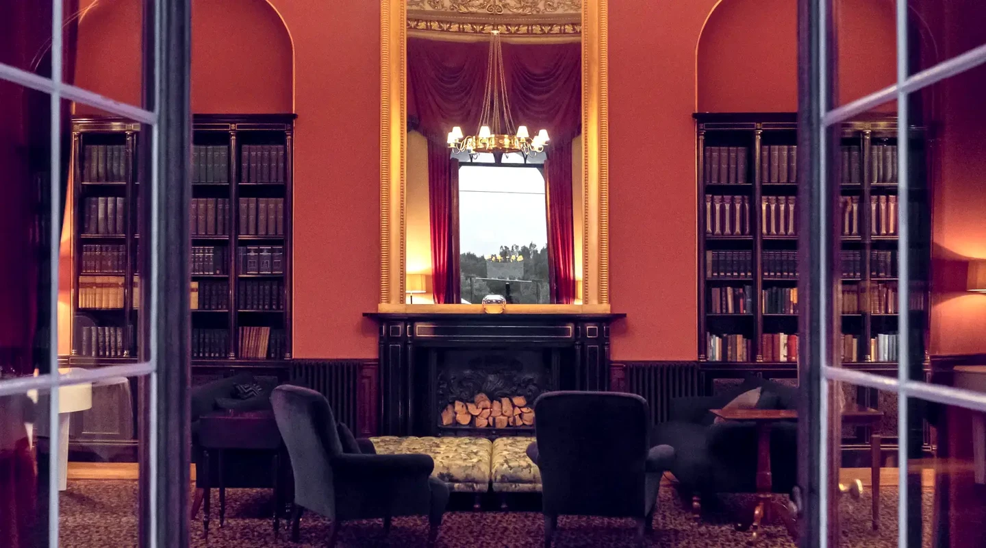 View into the old library with bookshelves, sofas, large mirror, and fireplace