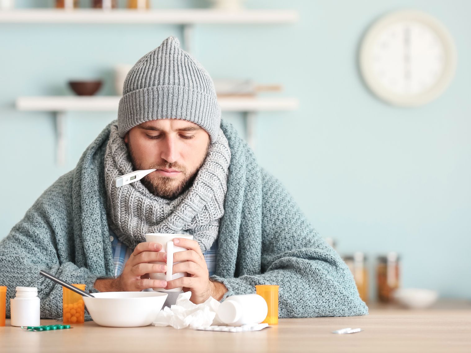 Mann sitzt mit Erkältung krank am Küchentisch