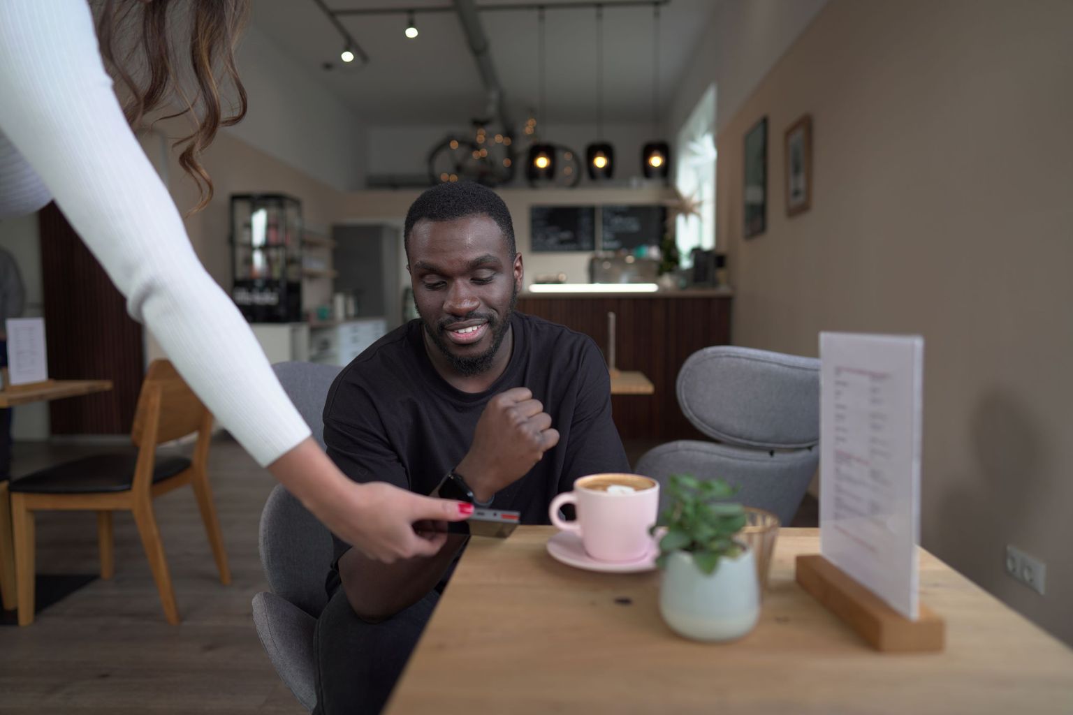 Kunde bezahlt in einem Café kontaktlos mit einer Smartwatch