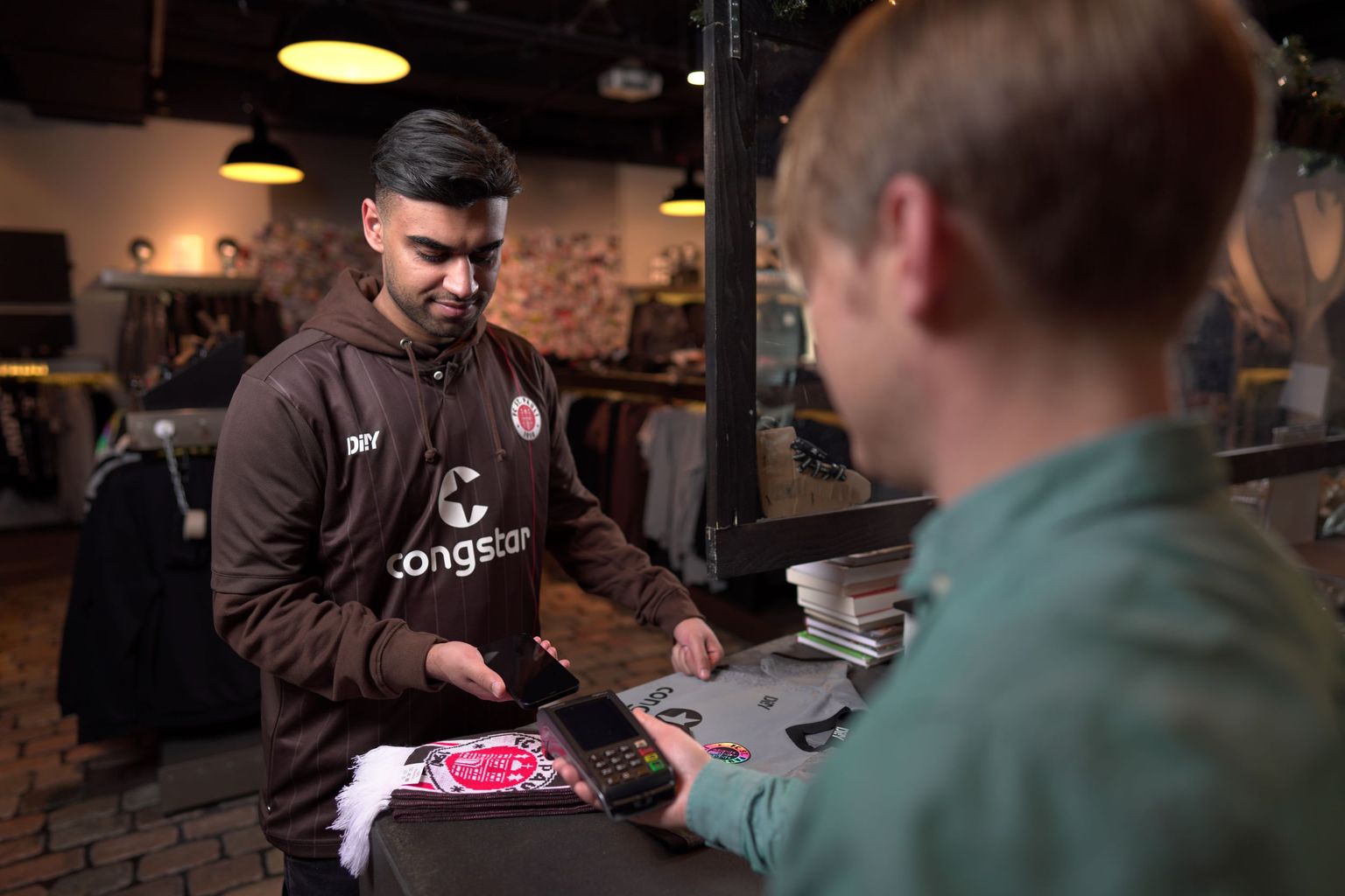 FC St. Pauli Fan kauft Trikot und Schal im Fanshop