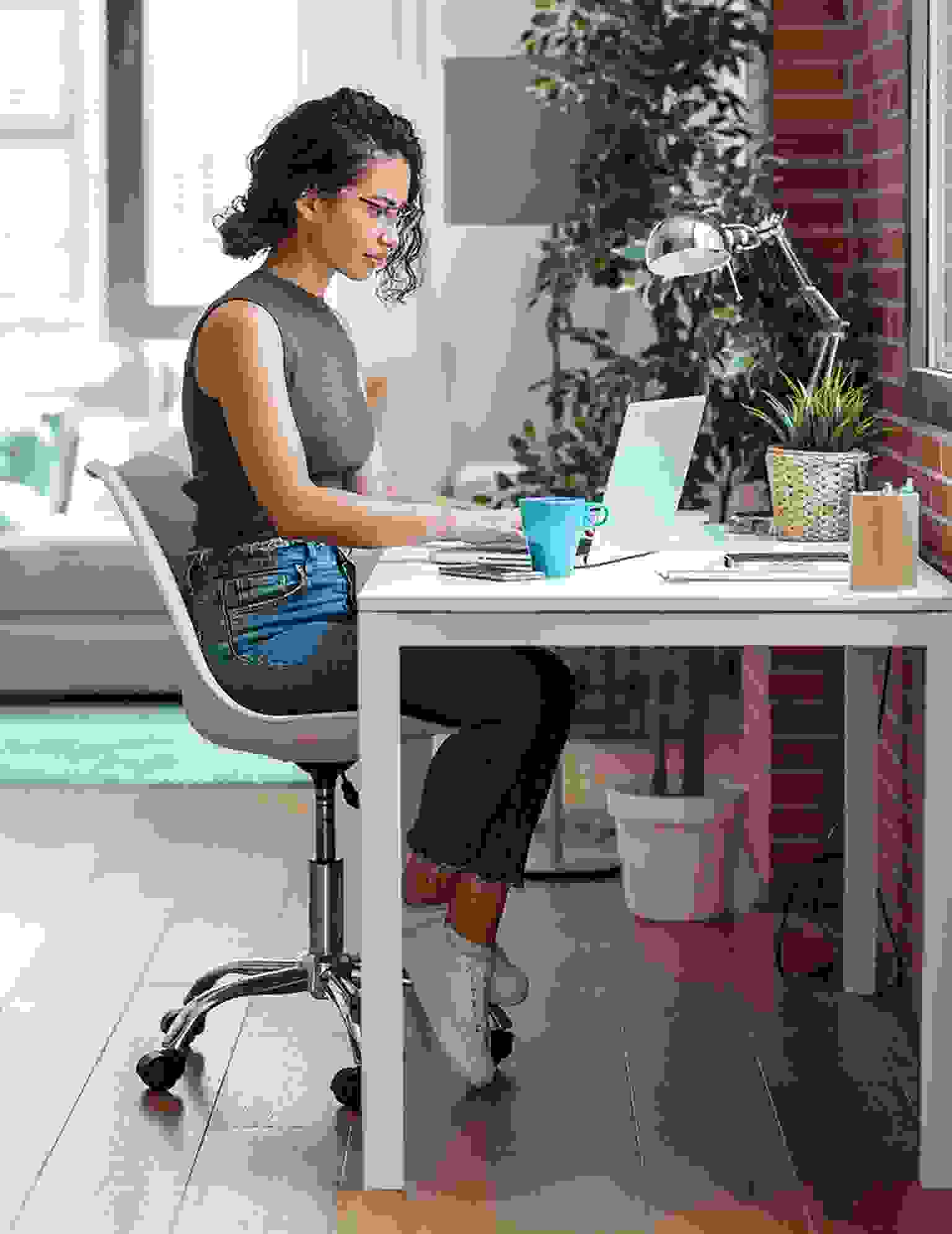 A woman sitting on her desk, working on her laptop