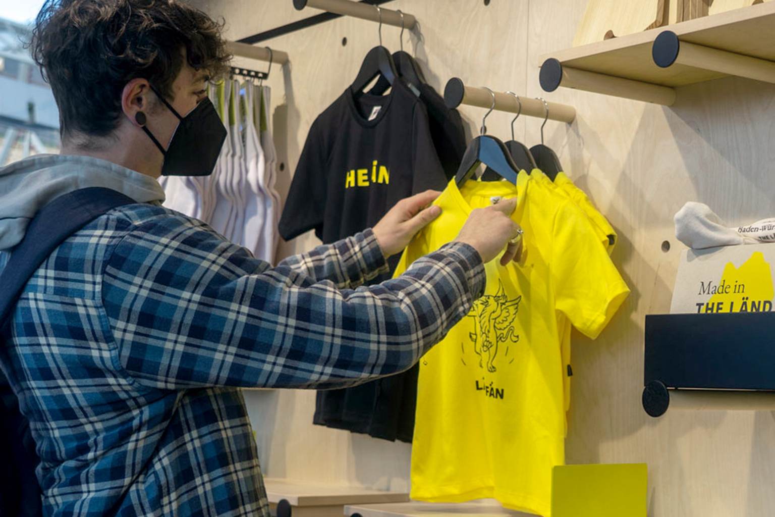 Ein Mann schaut sich Merchandise von "THE LÄND" in einem Laden an.