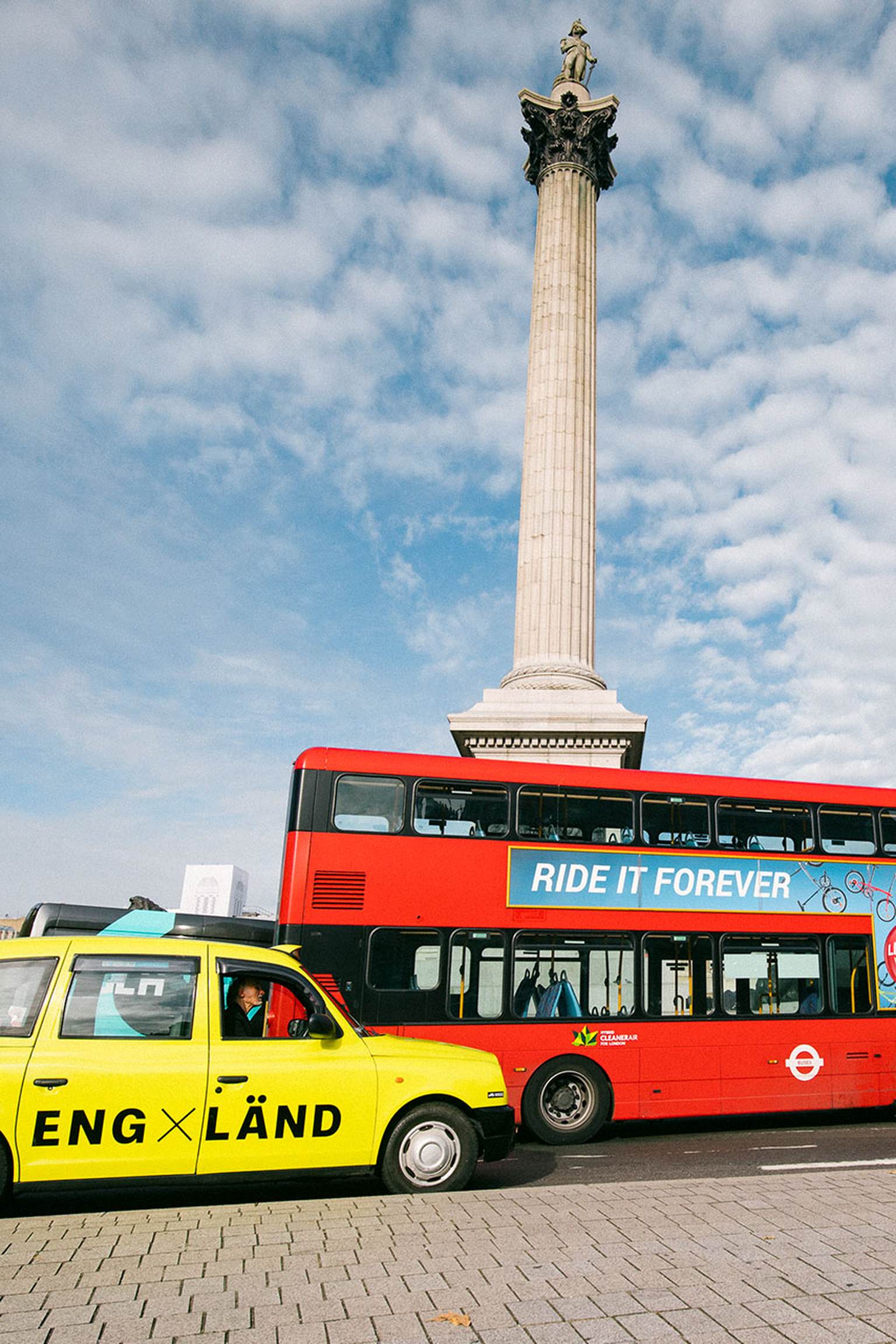 A neon yellow cab and a red tourist bus are standing in front of the Buckingham Palace in England.