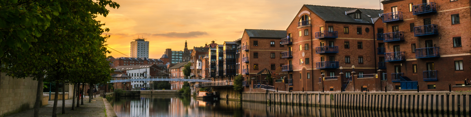 Redeveloped warehouses and modern bridge on the River Aire in Leeds at sunset