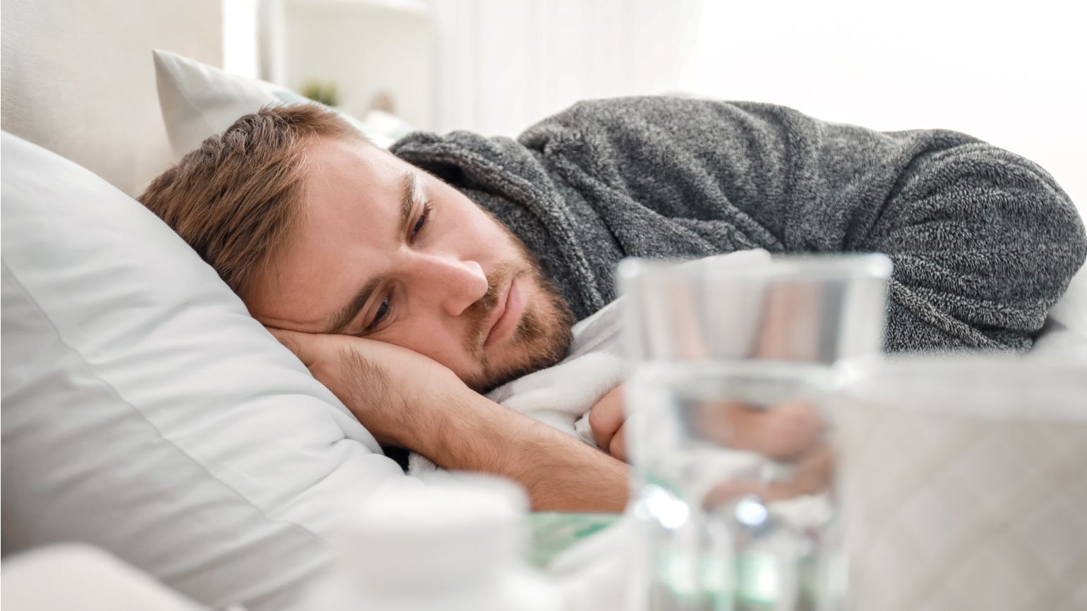 Mann liegt mit Grippe oder Erkältung im Bett