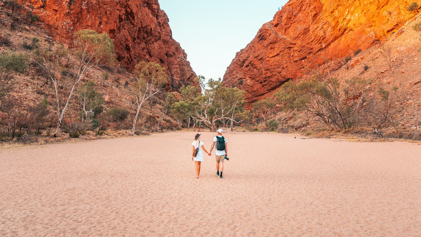 Young couple holding hands and walking towards Simpsons Gap