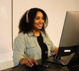 Woman with headphones looking at a computer screen