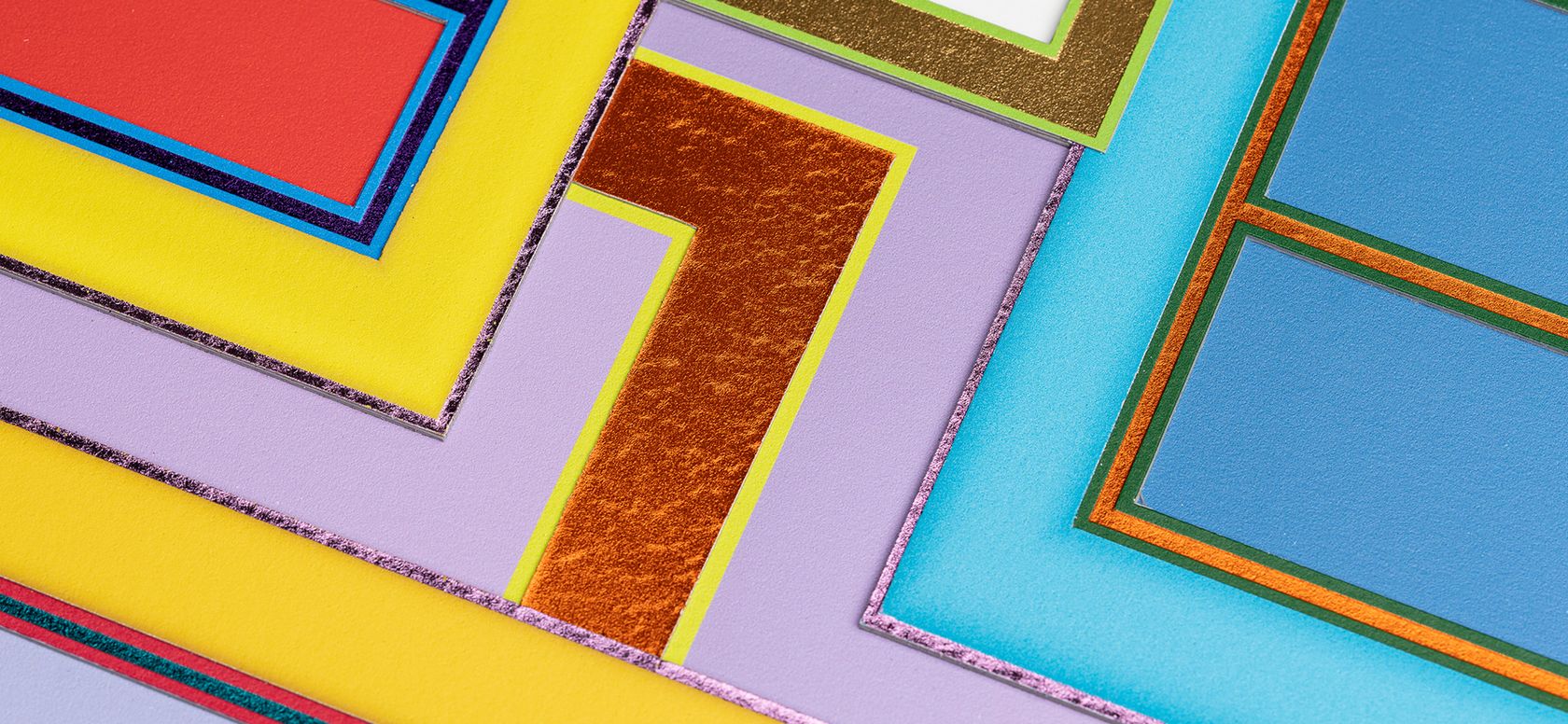 on-angle close up of a colourful, rectilinear print centred on an l-shaped section of metallic orange