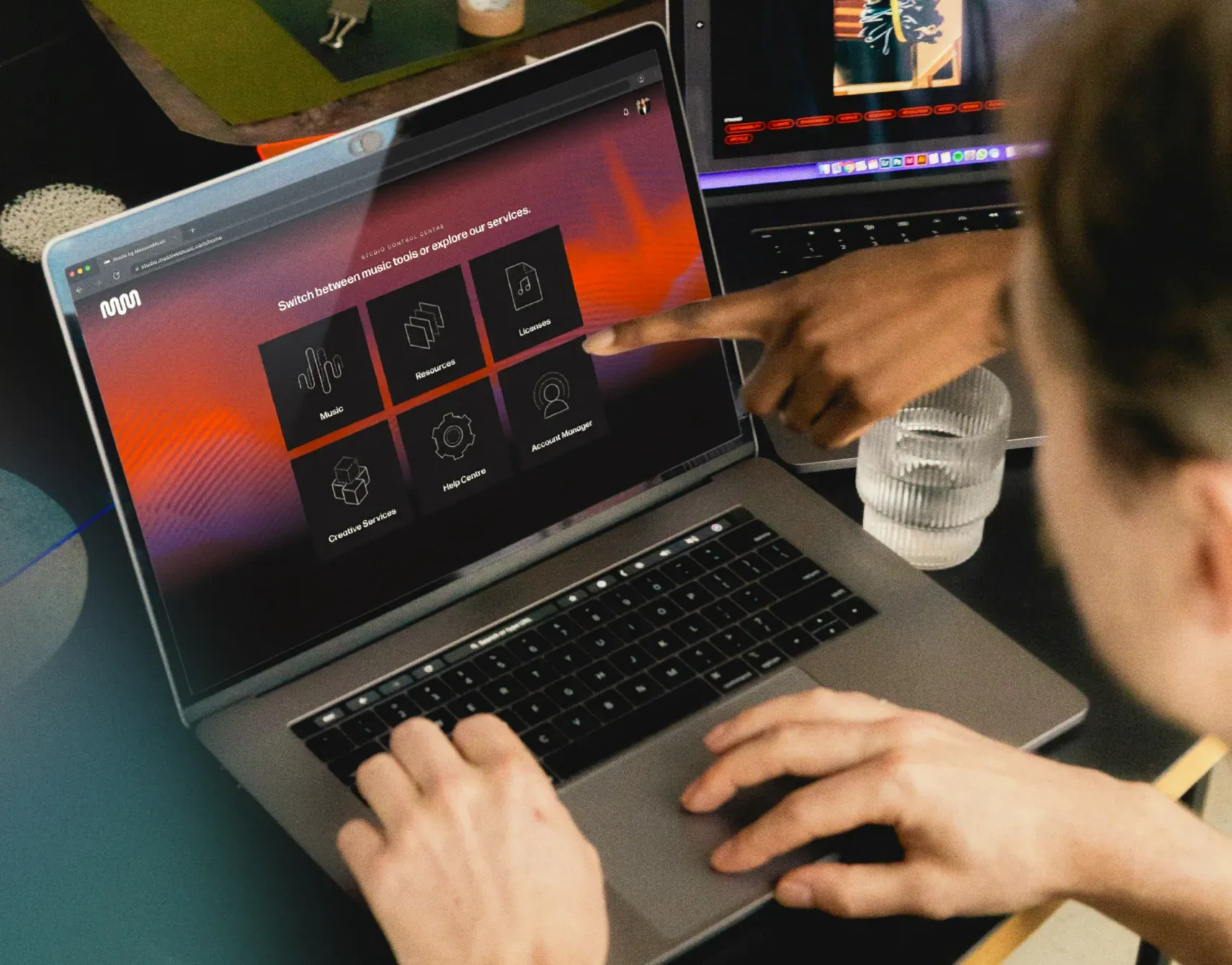 Colleagues pointing at a music management platform on a laptop, choosing brand-safe, licensed tracks together