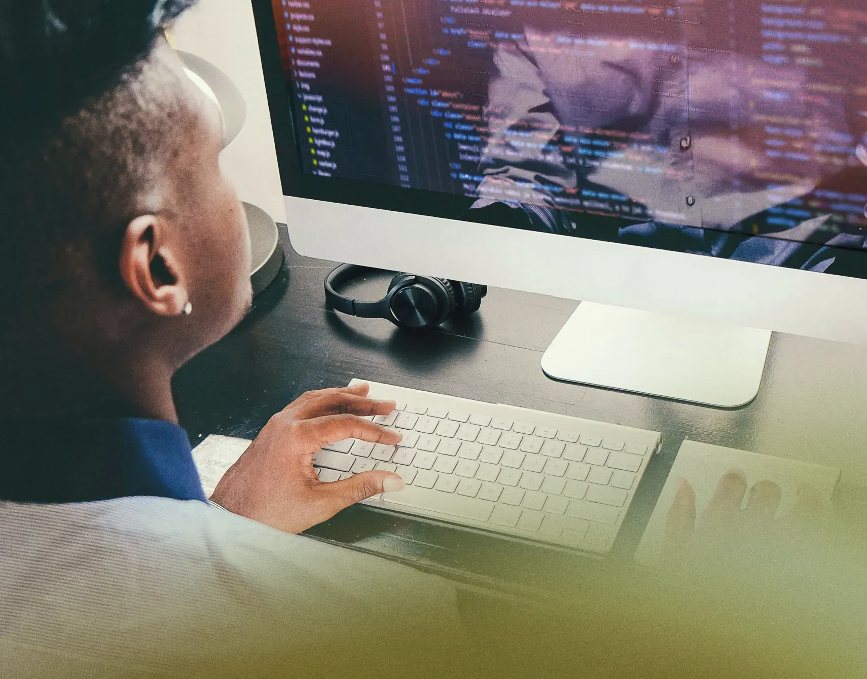 Person curating music metadata at a desktop computer with headphones beside the keyboard, for ethical AI metadata generation