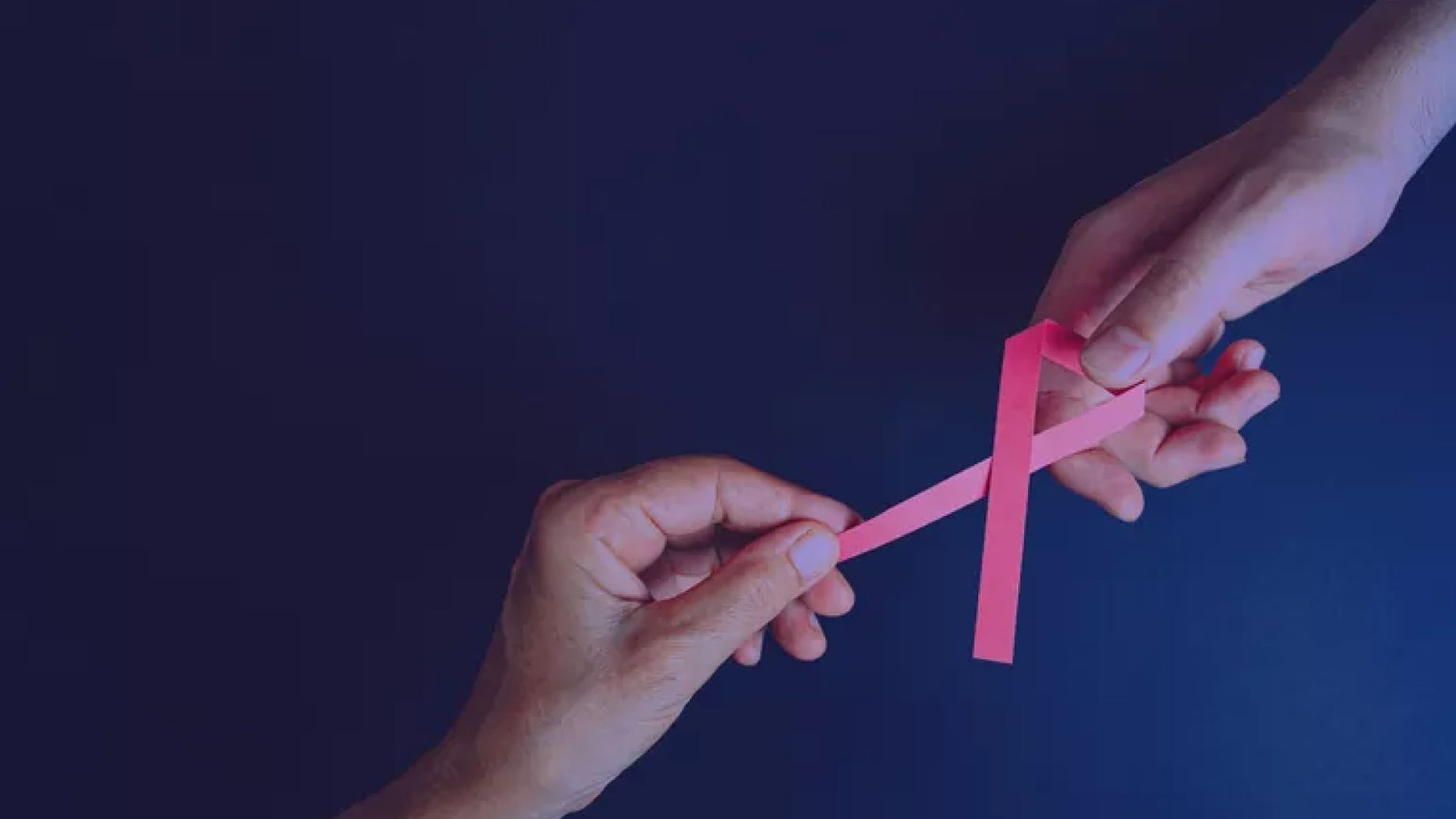 Two hand holding a ping ribbon in the shape of breast cancer awareness symbol