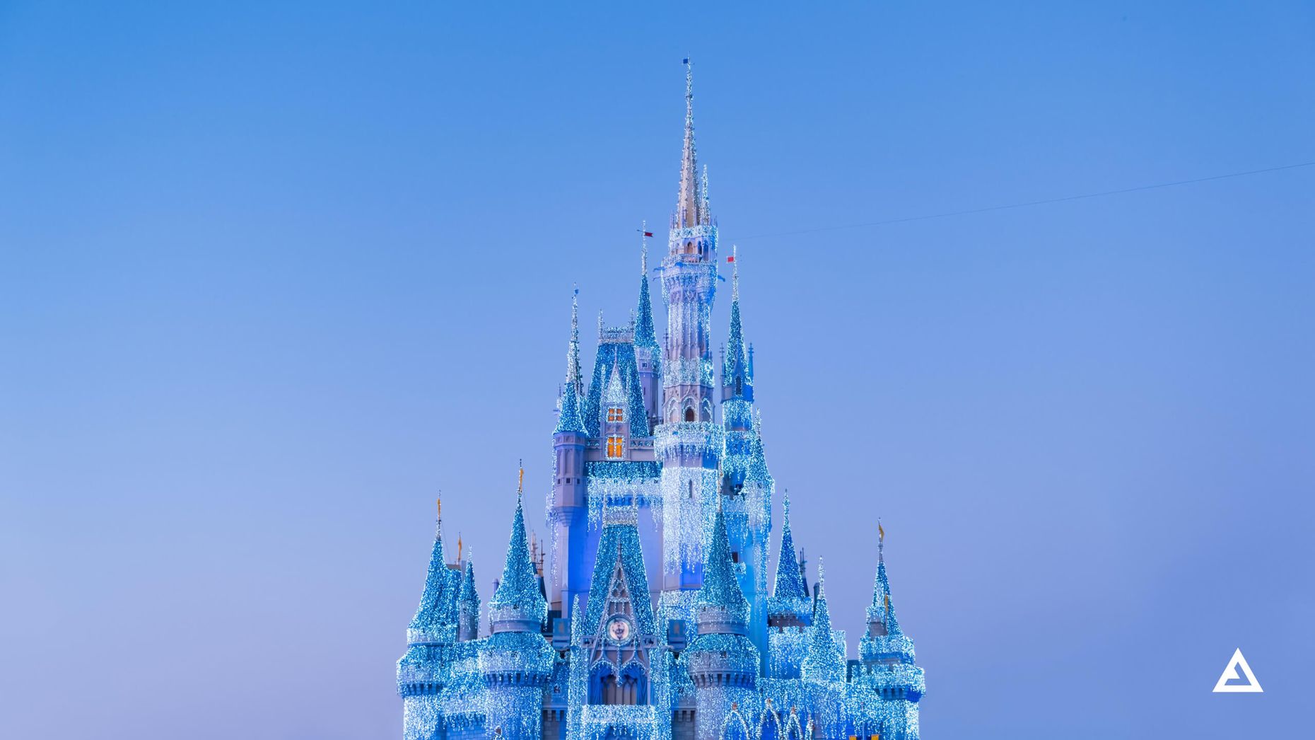 A Disney castle lit up in dazzling blue Christmas lights