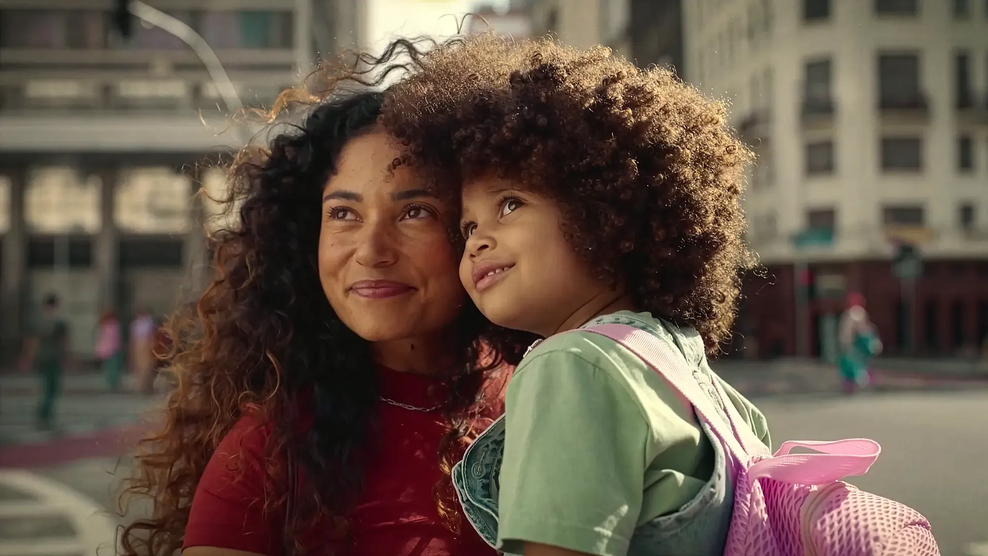 Mother carrying her daughter through a sunlit city street, from Dove's The Code campaign film