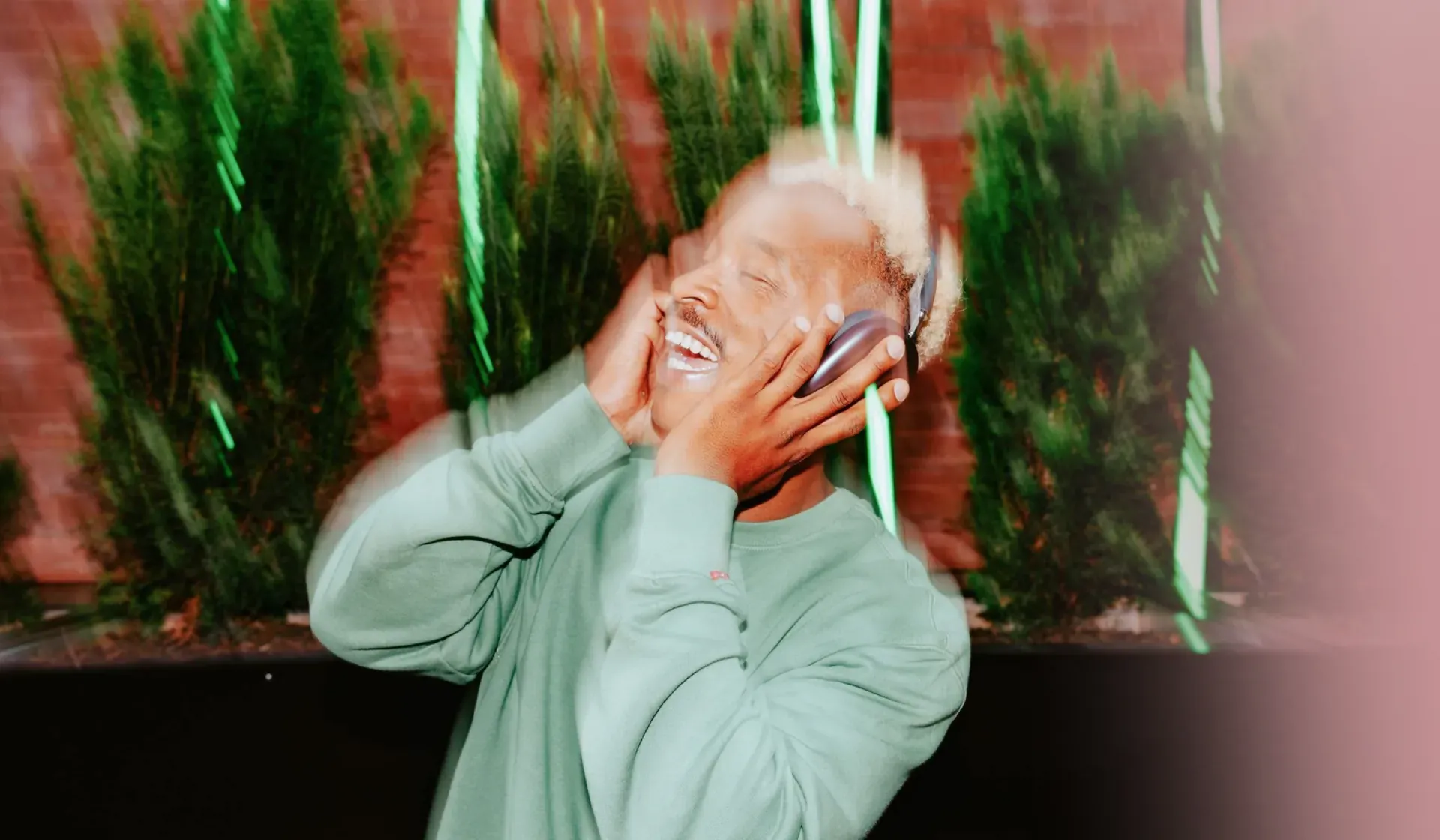 Listener in headphones against a brick wall, for MassiveMusic's guide to what sonic branding is