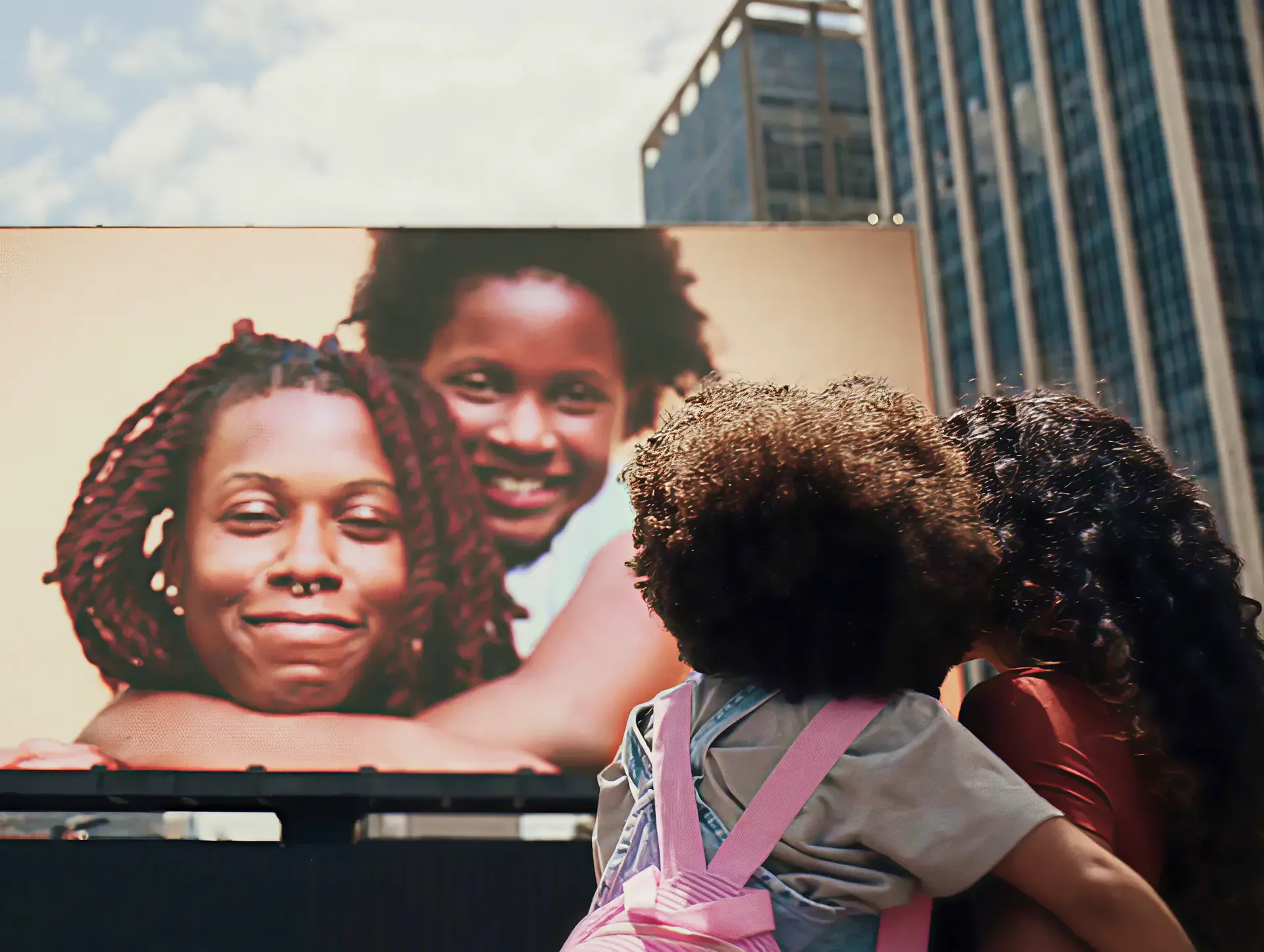Mother and daughter looking up at a city billboard showing their smiling portraits, from Dove's The Code film