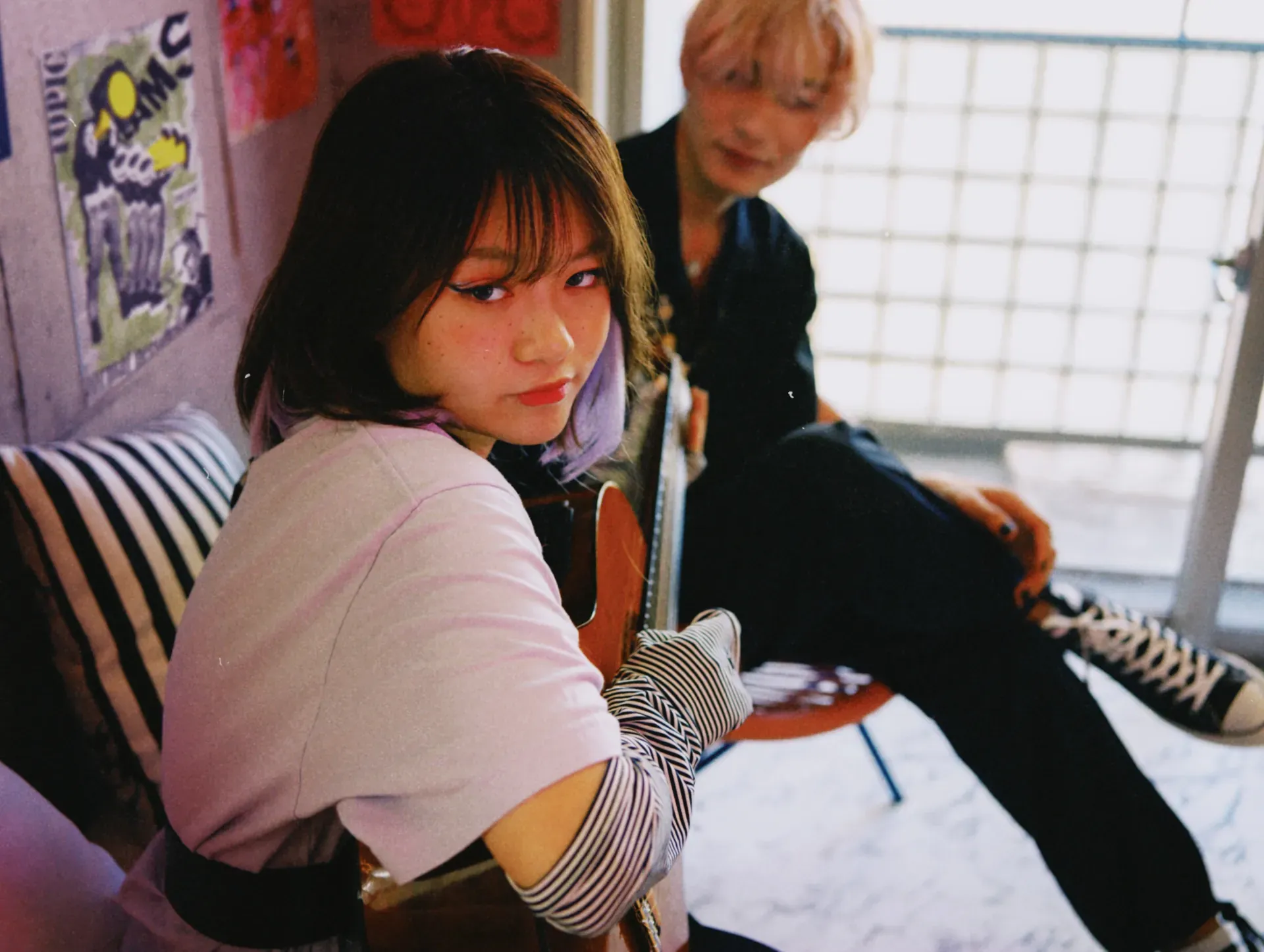 Young guitarist with a friend in a poster-lined room, hinting at GRAI's co-creative vision for music