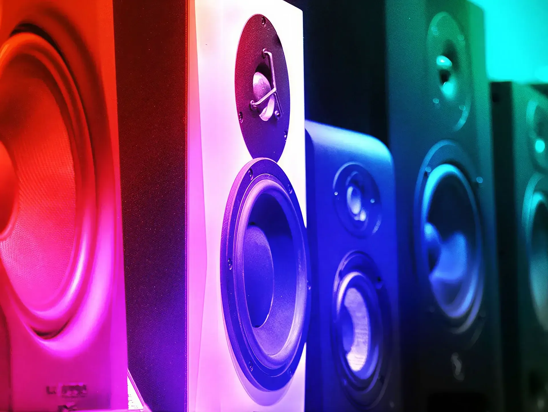 Row of music speakers lit in red, purple, blue and green stage lighting representing curated sound systems