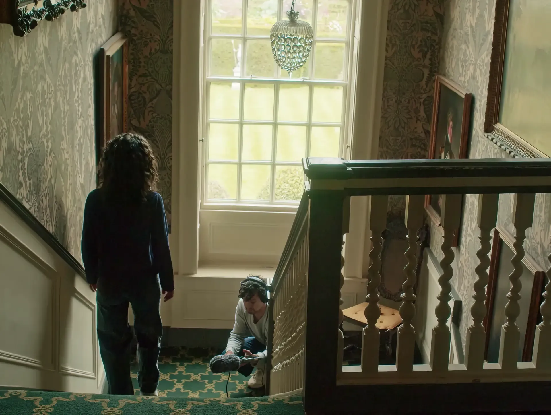 Woman by a tall window beside a staircase in a National Trust historic house, Sound of National Trust