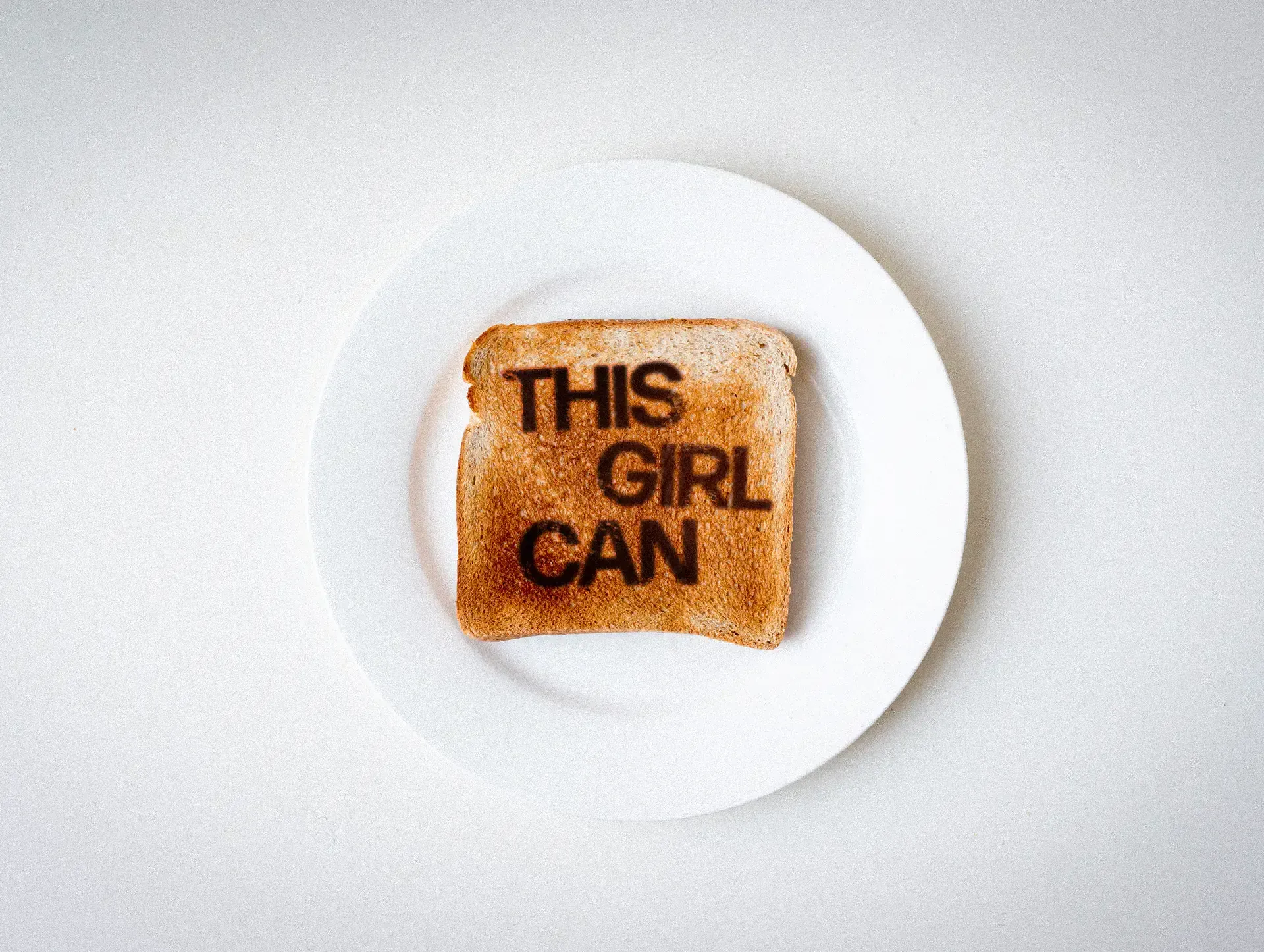 Slice of toast stamped with the This Girl Can logo on a white plate