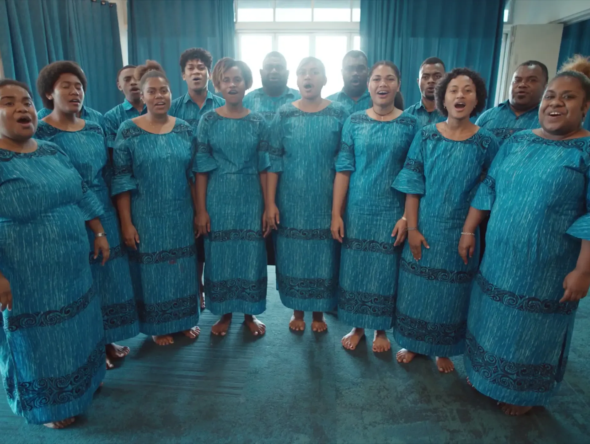 Choir of women in blue traditional dresses singing, recorded for the Sound of Fiji Airways campaign