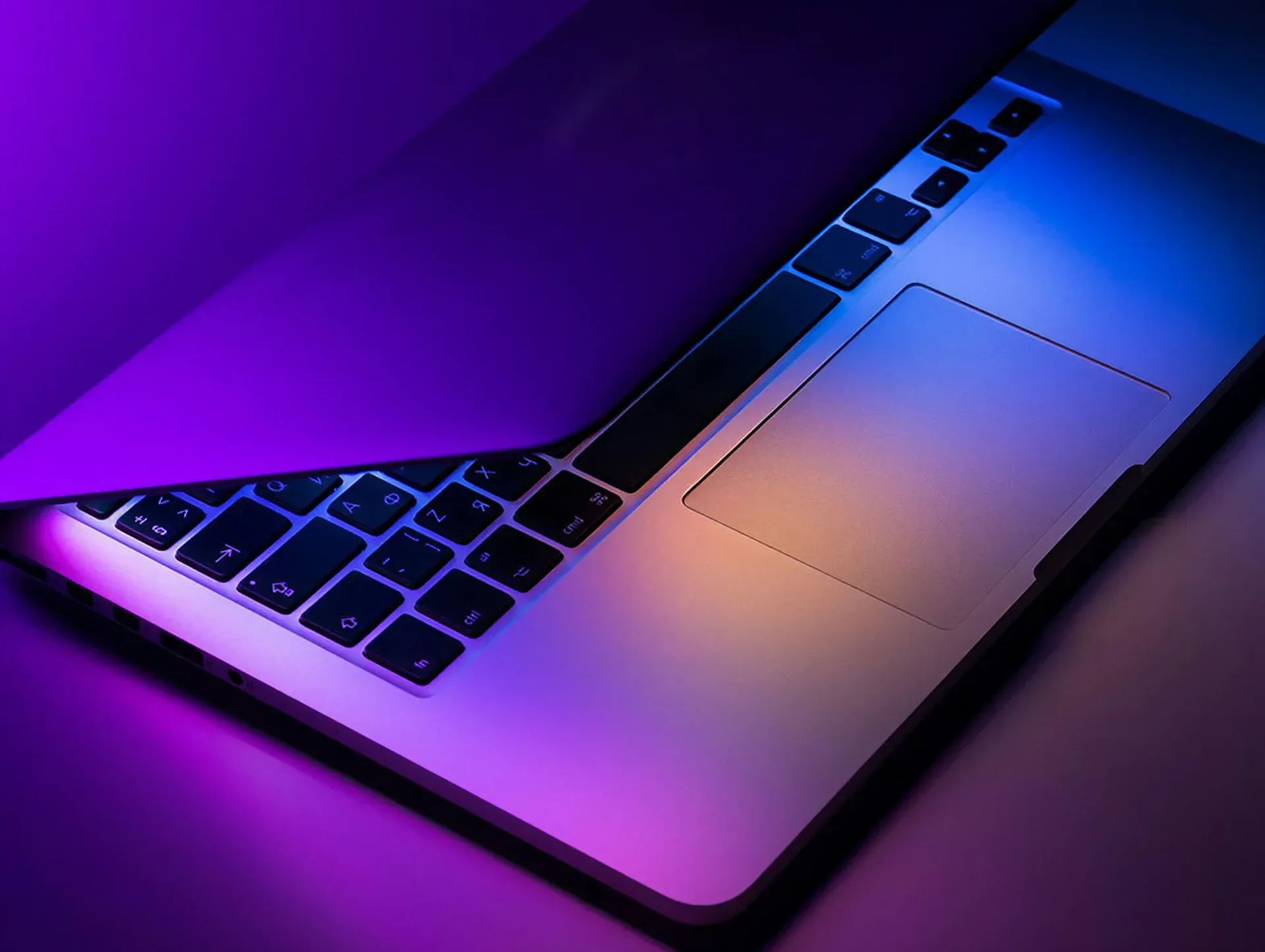 Open laptop on a desk lit by colorful purple stage lighting, illustrating ambient music for spaces