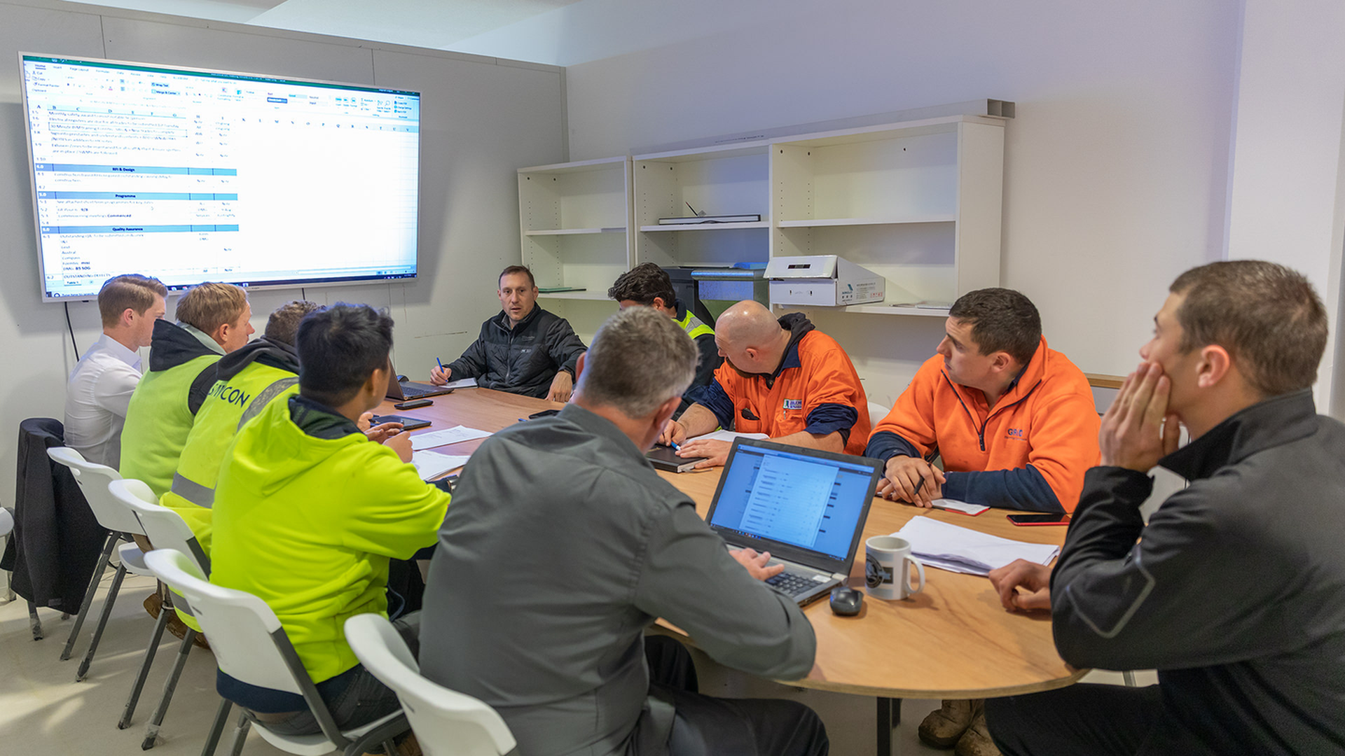 Construction workers discussing construction submittals over software.
