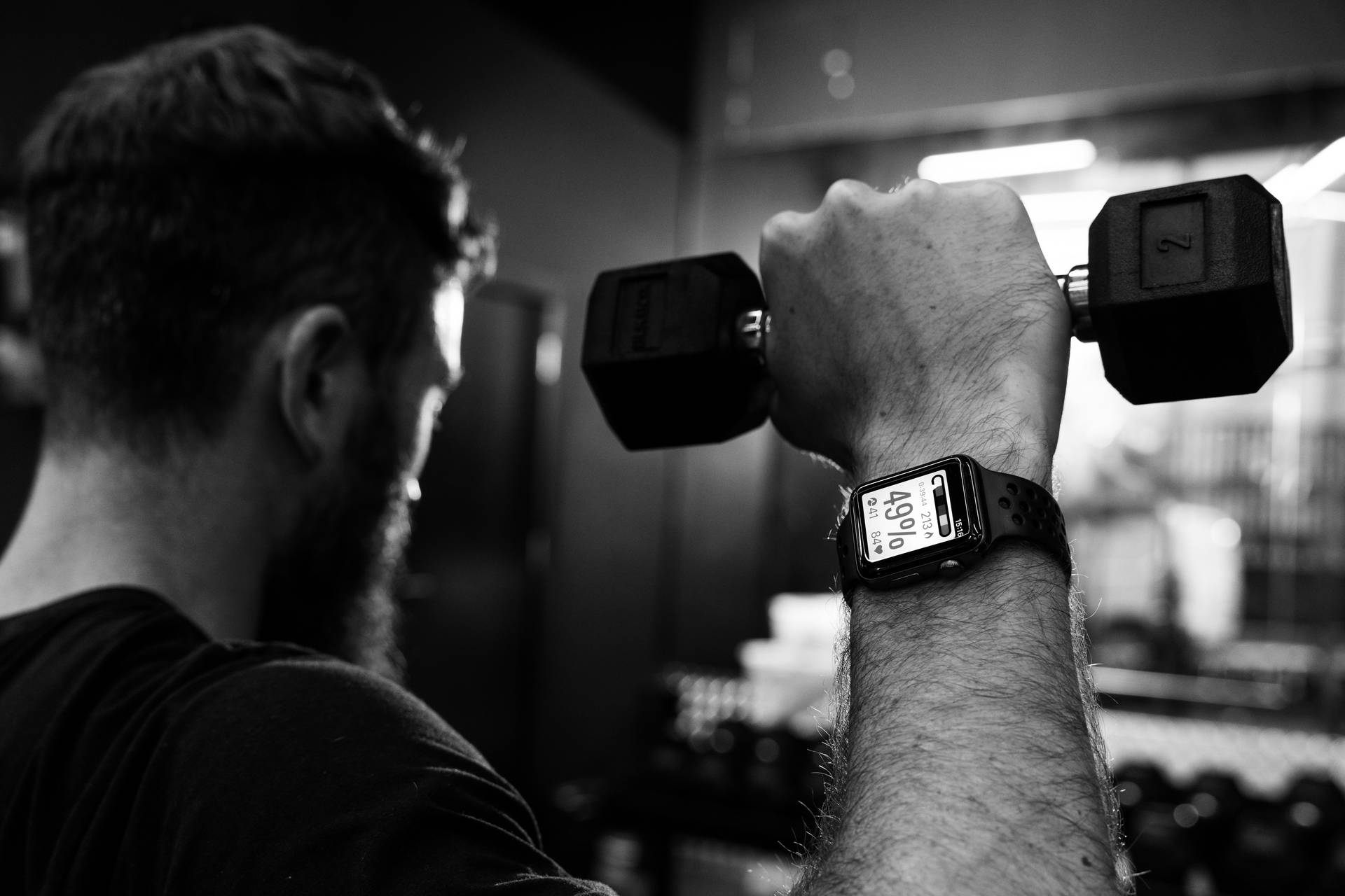A man lifting a 2kg dumbbell wearing a watch linked to MyZone