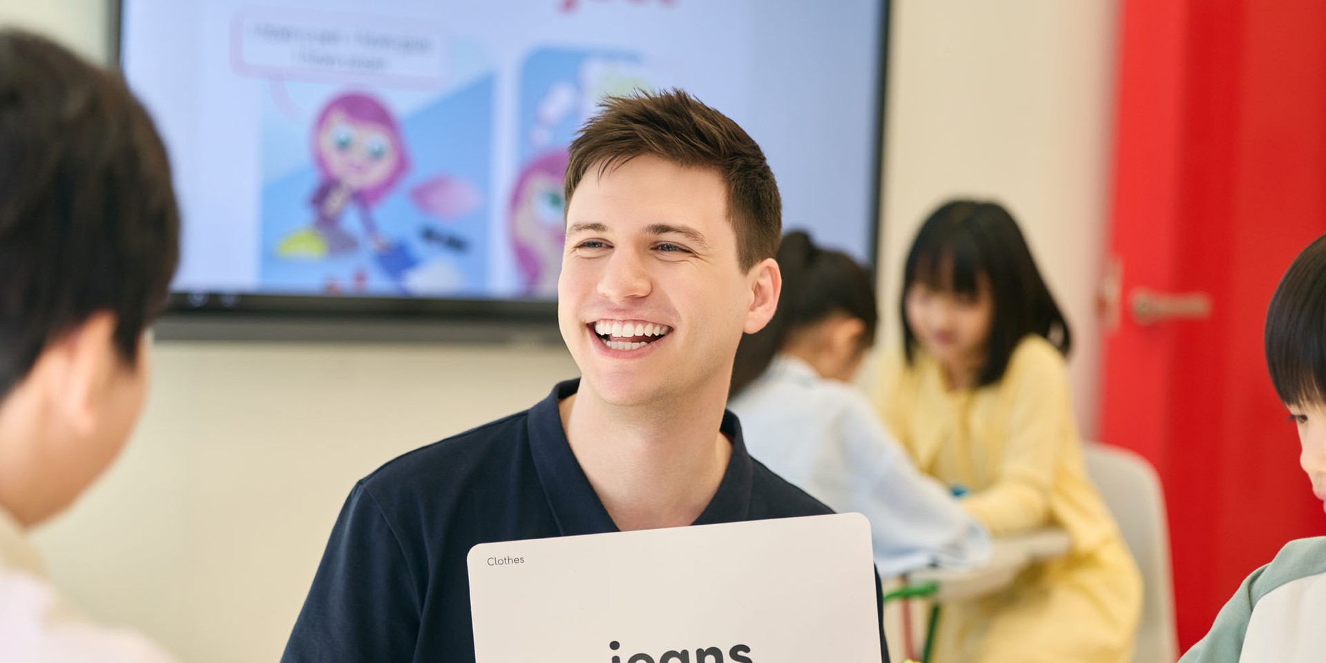 teacher holding a flashcard and smiling while teaching