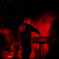 DJ op een podium van TWOFIFTYK, in rood licht binnen een geometrische lichtkoepel