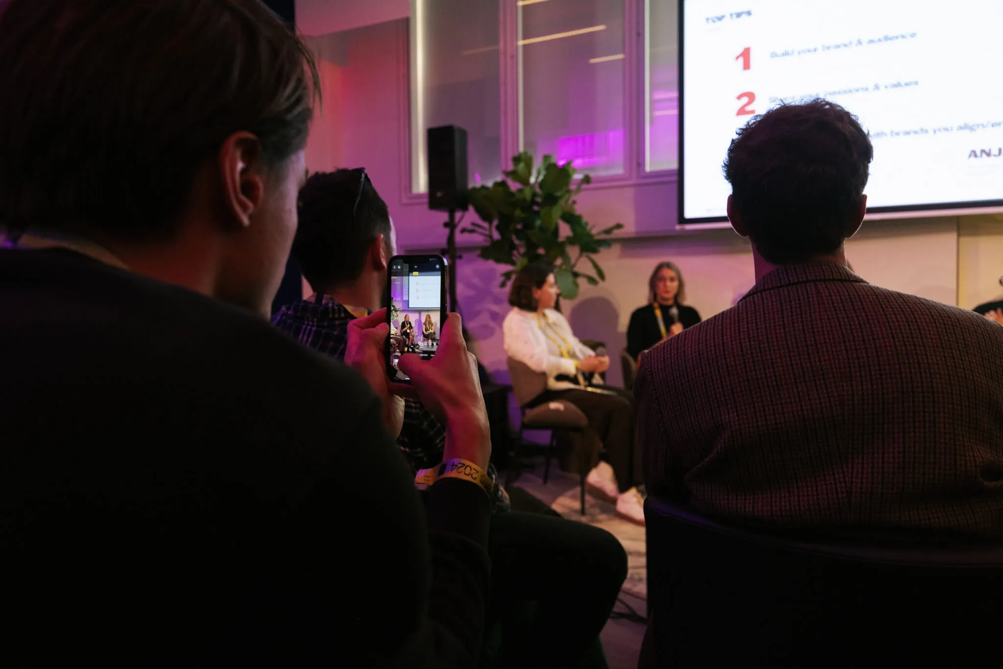 Audience member photographing MassiveMusic's 'Beyond Streaming' panel discussion at ADE, with a large screen displaying text in the background.