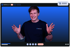 Smiling person in a dark shirt gesturing enthusiastically during an online webinar, with a blue gradient background and participant counter at 5000.