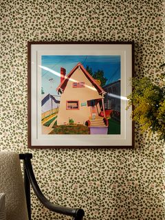 frame print of a house on a wall with patterned green wallpaper