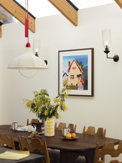 Framed print on the wall of a brightly-lit kitchen, with an enticing spread on the dining table