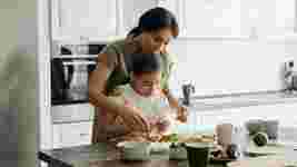 Mother and child preparing food in a white kitchen