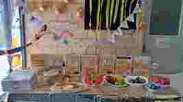 A decorated table with snacks, fruits, and instructional posters for R U OK? Day. Gold balloons and colorful garlands hang above.