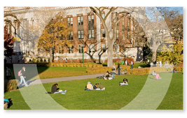 A view of a university campus with students lying in a park