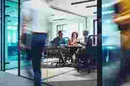 Business people meet in a glass office to transform client journeys